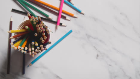 Overhead-Shot-Of-Hand-Choosing-Pencil-From-Pot-On-Marble-Background