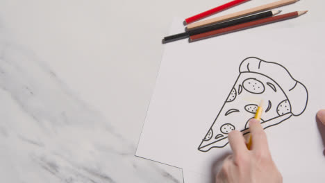 Overhead-Shot-Of-Person-Colouring-In-Picture-Of-Pizza-On-Marble-Background