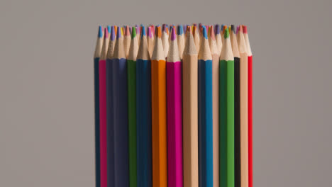 Studio-Shot-Of-Rotating-Multi-Coloured-Pencils-Against-Grey-Background-