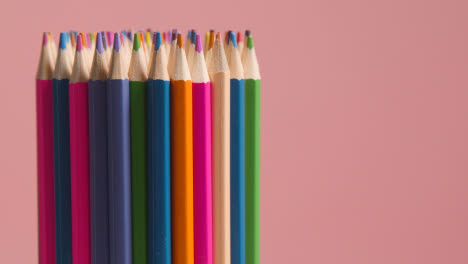 Studio-Shot-Of-Rotating-Multi-Coloured-Pencils-Against-Pink-Background-1