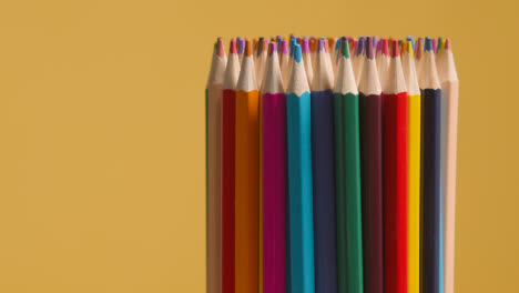 Studio-Shot-Of-Multi-Coloured-Pencils-Against-Yellow-Background-