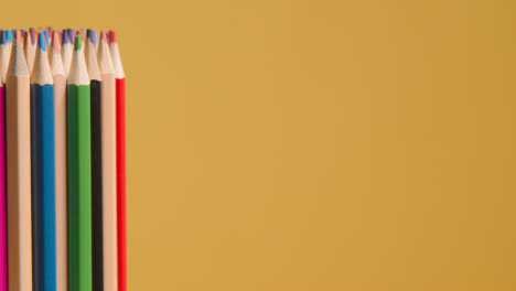 Studioaufnahme-Von-Rotierenden-Mehrfarbigen-Bleistiften-Vor-Gelbem-Hintergrund