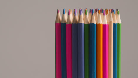Studio-Shot-Of-Multi-Coloured-Pencils-Rotating-Against-Grey-Background-
