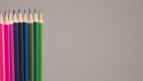 Studio-Shot-Of-Rotating-Line-Of-Multi-Coloured-Pencils-Against-Grey-Background-1