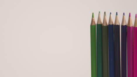 Studio-Shot-Of-Rotating-Line-Of-Multi-Coloured-Pencils-Against-White-Background-