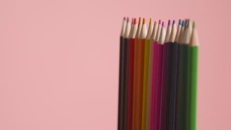 Studio-Shot-Of-Rotating-Line-Of-Multi-Coloured-Pencils-Against-Pink-Background-1
