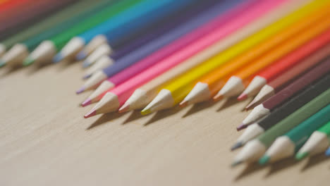 Lápices-De-Colores-En-Una-Línea-Sobre-Fondo-De-Madera-Con-Una-Persona-Que-Elige-Una-Rosa