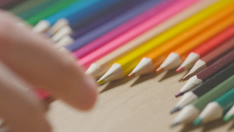 Lápices-De-Colores-En-Una-Línea-Sobre-Fondo-De-Madera-Con-Una-Persona-Que-Elige-Rosa-1