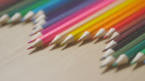 Coloured-Pencils-In-A-Line-On-Wooden-Background-With-Person-Replacing-Pink-One-3