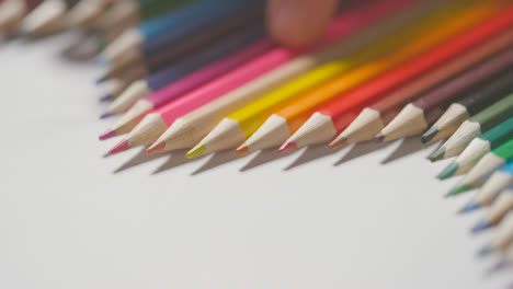 Studioaufnahme-Von-Mehrfarbigen-Bleistiften-In-Einer-Linie-Auf-Weißem-Hintergrund-Mit-Der-Hand,-Die-1-Auswählt