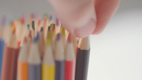 Close-Up-Of-Person-Picking-Up-Black-Pencil-From-Pot-Of-Multi-Coloured-Pencils