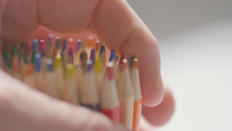 Close-Up-Of-Person-Picking-Up-And-Dropping-Multi-Coloured-Pencils-From-Pot