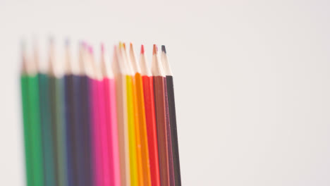 Studio-Shot-Of-Line-Of-Multi-Coloured-Pencils-Against-White-Background-With-Differential-Focus