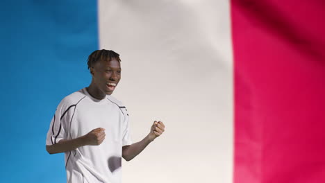 Young-Footballer-Celebrating-to-Camera-In-Front-of-France-Flag-