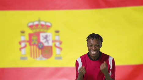 Young-Footballer-Celebrating-to-Camera-In-Front-of-Spain-Flag-