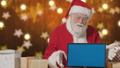 Santa-Claus-Using-a-Laptop-with-Blue-Screen-at-His-Desk