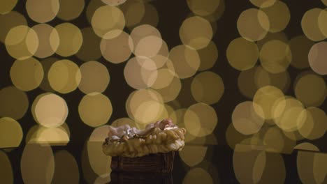Studio-Christmas-Scene-With-Figure-Of-Baby-Jesus-In-Manger-From-Nativity-With-Lights