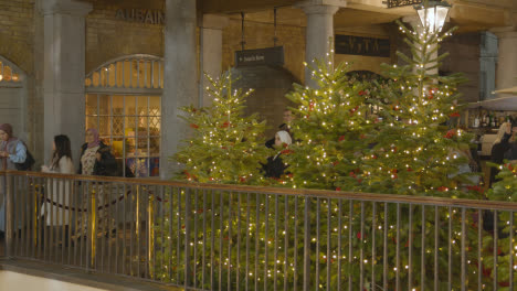 Luces-Y-Decoraciones-Del-árbol-De-Navidad-Con-Compradores-En-Covent-Garden,-Londres,-Reino-Unido-Por-La-Noche-3