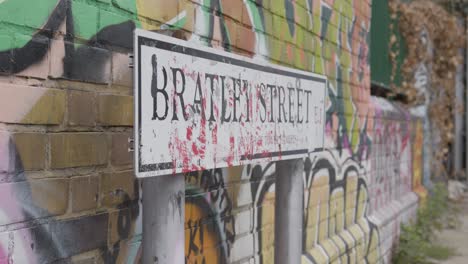 Nahaufnahme-Des-Straßenschildes-Im-Innenstadtbereich-Mit-Graffiti-An-Der-Wand-Hinter-London,-Großbritannien