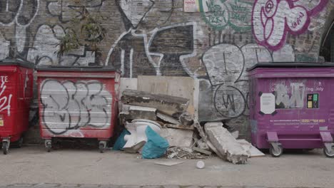 Rubbish-And-Wheelie-Bins-In-Front-Of-Graffiti-Covered-Wall-In-Tower-Hamlets-London-UK-1