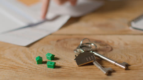 Hauskaufkonzept-Mit-Schlüsseln-Am-Hausförmigen-Schlüsselring-Und-Person,-Die-Finanzen-überprüft-10