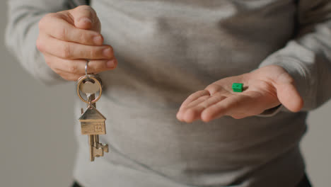 Hauskaufkonzept-Mit-Person,-Die-Schlüssel-Auf-Hausförmigem-Schlüsselring-Und-Grünem-Vorbildhaus-Hält