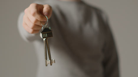 Hauskaufkonzept-Mit-Person,-Die-Schlüssel-Auf-Hausförmigem-Schlüsselring-Vor-Grauem-Hintergrund-Hält-5