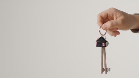 Hauskaufkonzept-Mit-Person,-Die-Schlüssel-Auf-Hausförmigem-Schlüsselring-Vor-Weißem-Hintergrund-Hält