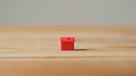 Home-Buying-Concept-With-Red-Plastic-Model-Of-House-On-Wooden-Surface-1