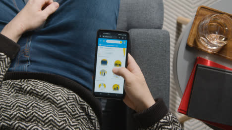 Overhead-Shot-Of-Person-At-Home-Shopping-Online-Looking-At-Walmart-Website-On-Mobile-Phone