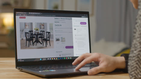 Person-At-Home-Shopping-Online-Looking-At-Wayfair-Website-On-Laptop