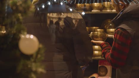 Close-Up-Customers-At-Stall-Selling-Tibetan-Singing-Bowls-At-Christmas-Market-On-London-South-Bank-At-Night
