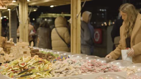 Nahaufnahme-Kunden-Am-Stall-Verkaufen-Süßigkeiten-Auf-Dem-Weihnachtsmarkt-Am-Londoner-South-Bank-In-Der-Nacht