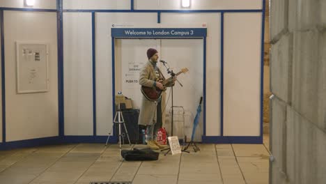 Busker-Playing-Guitar-In-Subway-At-Night