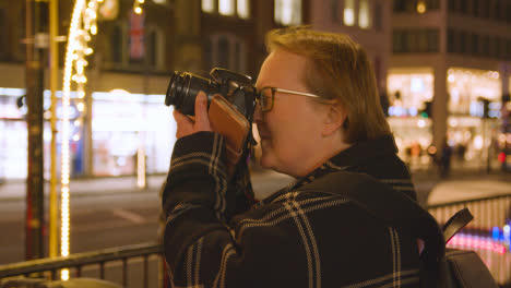 Tourist-Taking-Photo-Of-Christmas-Lights-Outside-Harrods-Department-Store-In-London