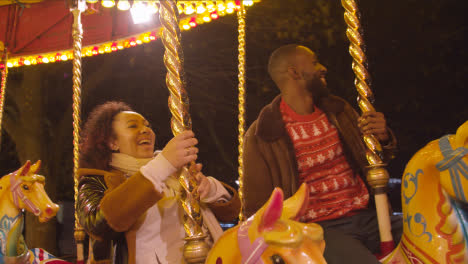 Couple-Having-Fun-Riding-On-Fairground-Roundabout-On-London-South-Bank-At-Night-1