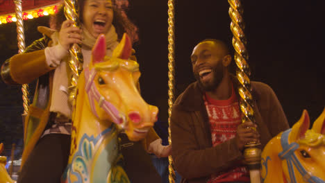 Couple-Having-Fun-Riding-On-Fairground-Roundabout-On-London-South-Bank-At-Night-2