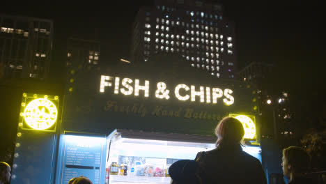 Illuminated-Sign-Above-Fish-And-Chip-Stall-On-London-South-Bank-At-Night