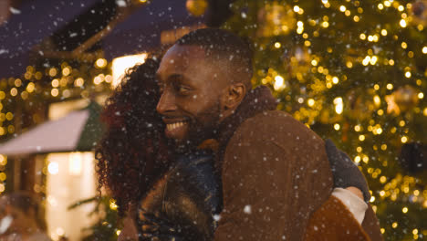 Couple-Hugging-As-They-Meet-In-Front-Of-Christmas-TreeWhen-Snowing-in-London