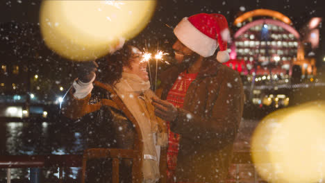 Couple-Celebrating-Christmas-Or-New-Year-With-Sparklers-Whilst-Snowing-in-London