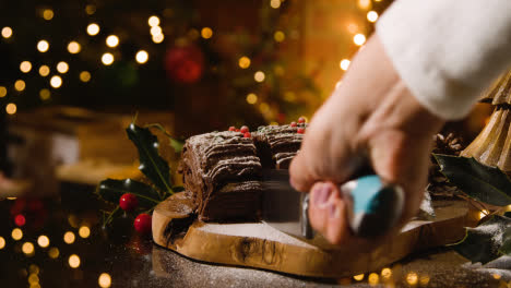 Christmas-Food-At-Home-And-Slice-Being-Cut-From-Traditional-Yule-Log-Dusted-With-Icing-Sugar