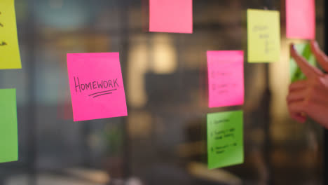 Close-Up-Of-Woman-Putting-Sticky-Note-With-Homework-Written-On-It-Onto-Transparent-Screen-In-Office-2