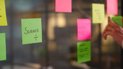 Close-Up-Of-Woman-Putting-Sticky-Note-With-Science-Written-On-It-Onto-Transparent-Screen-In-Office-2