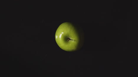Obenliegende-Studioaufnahme-Von-Grünem-Apfel,-Der-Sich-Vor-Schwarzem-Hintergrund-Dreht