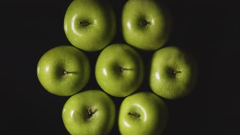 Obenliegende-Studioaufnahme-Von-Grünen-Äpfeln,-Die-Sich-Vor-Schwarzem-Hintergrund-Drehen