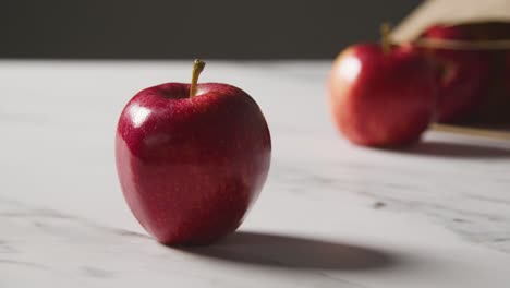 Studio-Shot-Of-Paper-Bag-Of-Red-Apples-On-Marble-Kitchen-Surface