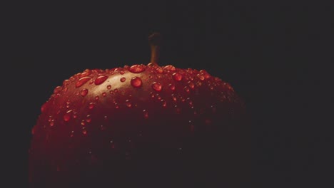 Nahaufnahme-Studioaufnahme-Von-Rotem-Apfel-Mit-Wassertröpfchen,-Die-Sich-Vor-Schwarzem-Hintergrund-Drehen