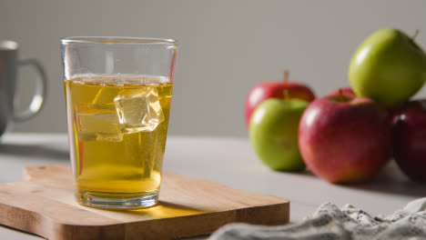 Glas-Apfelsaft-Mit-Eis-Und-Frischen-Äpfeln-Im-Hintergrund