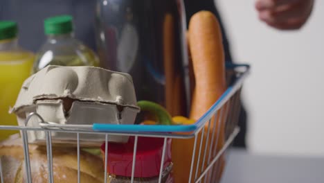 Close-Up-Of-Person-Unpacking-Basic-Food-Items-From-Supermarket-Wire-Shopping-Basket-