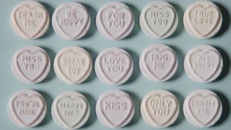 Full-Frame-Shot-Of-Person-Choosing-From-Heart-Candy-With-Romantic-Messages-Of-Love-On-Blue-Background